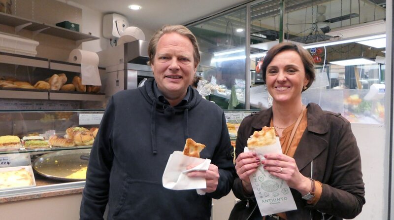 Die Genueser Köchin und Kochlehrerin Enrica Monzani und Spitzenkoch Björn Freitag (l) genießen auf dem Markt von Genua frisch gebackene Focaccia. – Bild: WDR/​2bild GmbH/​Franziska Reinhardt
