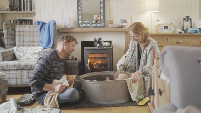 Baby Finn genießt beim Bad im Zuber den gemütlichsten Platz im Haus. Vor dem Feuer ist es kuschelig warm – im Gegensatz zum Rest des alten Hauses, in dem Sandy und Lars auf Colonsay leben. – Bild: SWR/​Johannes Kröger