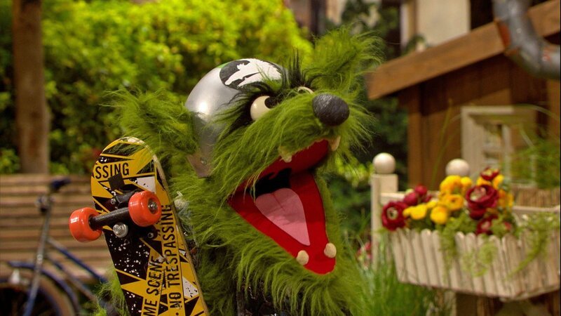 Der Wolf scheucht Wolle und Pferd von der Straße, weil er dort Skateboard fahren will. – Bild: NDR/​Sesame workshop