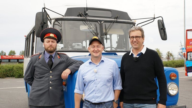 Tallinn in Estland. Ausflug: Soviet Flashback Tour mit Reiseleiter Bernd Wallisch und Kreuzfahrtdirektor Jörn Hofer. Ein ganz besonderer Ausflug in die alte Soviet-Zeit. Oberst Ivan (Tourguide Ivan heißt in Echt Jaan-Laur) steht schon bereit und erwartet sie am alten Soviet-Fahrzeug. – Bild: Deborah Stöckle /​ BR, Bewegte Zeiten Filmproduktion GmbH