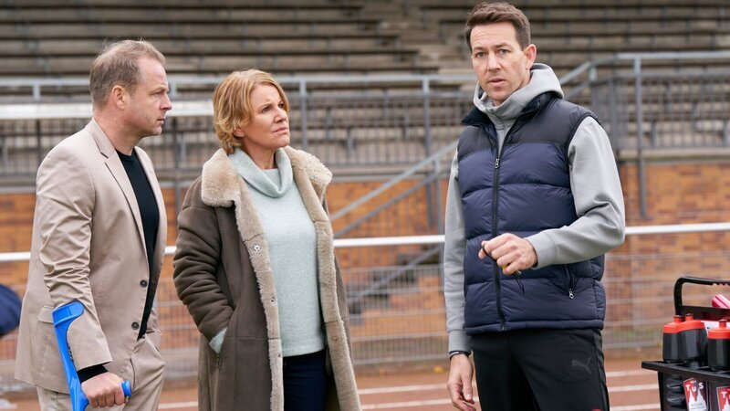 Marie Brand (Mariele Millowitsch, M.) und Jürgen Simmel (Hinnerk Schönemann, l.) befragen den Trainer Victor Holtmann (Florian Anderer, r.). – Bild: ZDF und Guido Engels