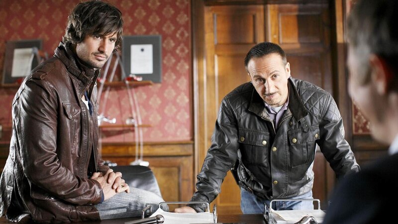 Ben (Tom Beck, l.) und Semir (Erdogan Atalay) sind auf die dubiosen Verbindungen von Rodenbach zu einem arabischen Staatsfonds gestoßen und fühlen dem Minister auf den Zahn. – Bild: TVNOW /​ Guido Engels