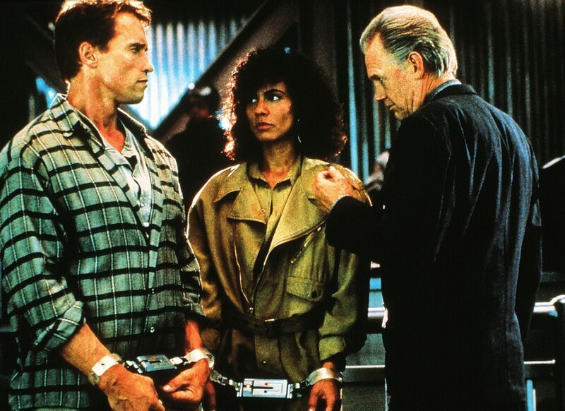 Mars-Diktator Cohaagen (Ronny Cox, re.) hat Doug (Arnold Schwarzenegger) und Melina (Rachel Ticotin) gefangen genommen. – Bild: RTL /​ Leonine Studios