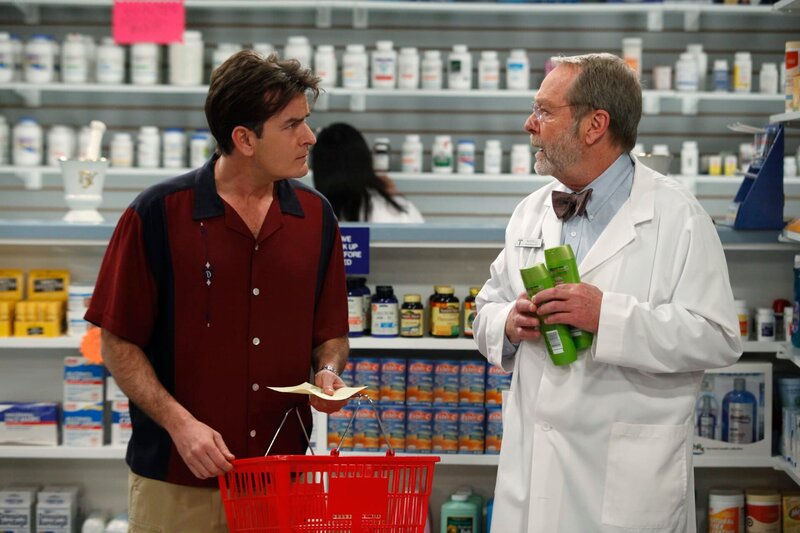Mit einer langen Einkaufsliste wird Charlie (Charlie Sheen, l.) von seiner Freundin Chelsea in die Apotheke geschickt. Russell (Martin Mull, r.) gibt ihm ein paar hilfreiche Tipps. – Bild: Warner Bros. Discovery /​ Greg Gayne