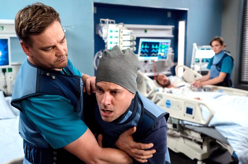 Frederick Stratmann bricht am Bett seines Ehemannes Sven Stratmann zusammen. Dr. Marc Lindner greift sofort ein. – Bild: ARD/​Jens-Ulrich Koch