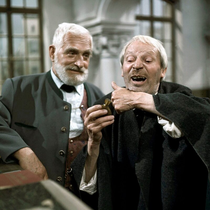 Dem gutmütig lächelndem Herrn Ökonom Josef Fäustl (Albert Hörrmann) führt der „Parasit“ (Ernst Bartels) seinen unappetitlichen Trick vor … – Bild: BR/​ZDF