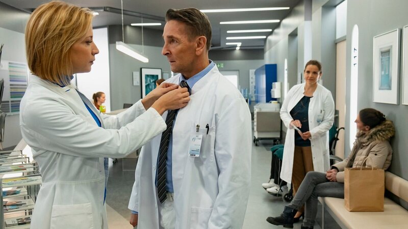 Ärztin richtet Arzt die Kravatte: Annika Ernst als Dr. Johanna Rüdiger, Mark Keller als Dr. Alexander Kahnweiler, Rebecca Immanuel als Dr. Vera Fendrich – Bild: SRF/​ZDF/​Erika Hauri