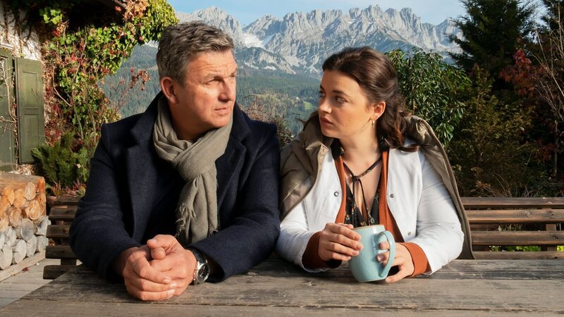 Der Bergdoktor Staffel 15 Was bleibt – Teil 1 Mann und junge Frau sitzen an Holztisch im Freien: Hans Sigl als Bergdoktor Dr. Martin Gruber, Ronja Forcher als Lilli Gruber – Bild: SRF/​ZDF/​Erika Hauri