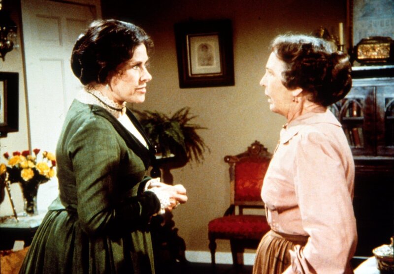 Mrs. Oleson (Katherine MacGregor, l.) erklärt Anna (Iris Korn, r.), dass sie durch ihre Liebe zu Reverend Alden dessen Stellung in der Kirche gefährdet. – Bild: Sat.1 Gold