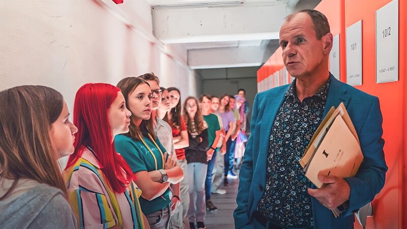 Herr Zech (Olaf Burmeister, re.) führt seine Exkursionsgruppe durch den Aktenkeller des Stasi-Unterlagen-Archivs. – Bild: mdr/​Saxonia Media/​Thomas Dietze