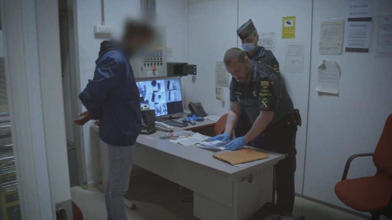 Ein Grenzpolizist kontrolliert die Papiere des Mannes. – Bild: Warner Bros. Discovery