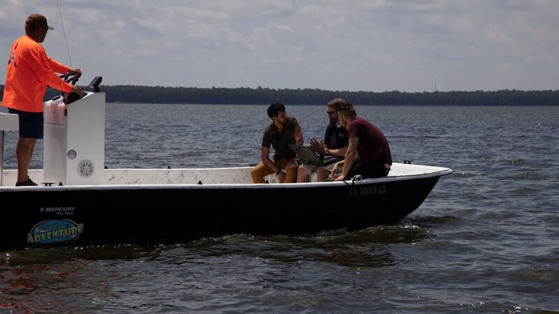 Wide shot of Justin and Emiliano sitting on a fan boat speaking with an expert. – Bild: Discovery channel