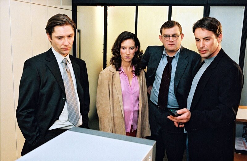 Kommissar Brandtner (Gedeon Burkhard, r.) lässt sich in der Privat-Bank von Kassierer Czermak (Nicki von Tempelhoff, l.), Sekretärin Tina Baumann (Maria Köstlinger, 2.v.l.) und dem Prokuristen Thomas Jäger (Martin Zauner, 2.v.r.) den Tathergang beschreiben. – Bild: SAT.1 /​ Ali Schafler