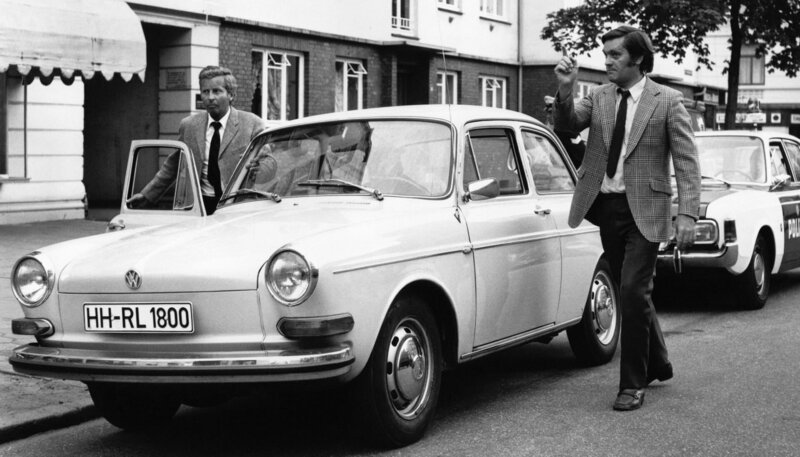 Die Geste des Kriminalbeamten Hartmann (Karl-Heinz Heß, rechts), der mit seinem Kollegen Schlüter (Eckart Dux) den diebischen Brüdern Merkel auf den Fersen ist. – Bild: NDR/​Lilo-Foto