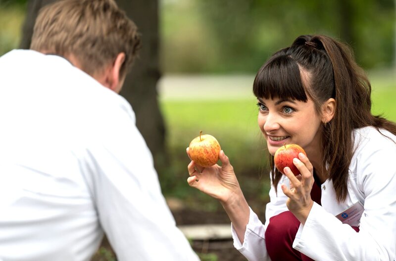 Dr. Annika Rösler (Paula Schramm, r.) versucht Dr. Lindner (Christian Beermann, l.) aufzumuntern, der mit starken Rückenschmerzen kämpft. – Bild: ARD/​Jens-Ulrich Koch