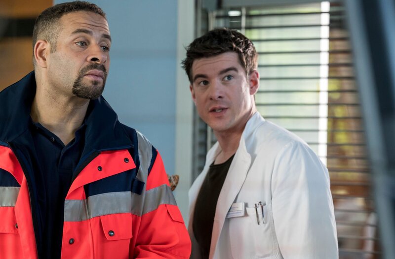 Matteo (Mike Adler, l.) ist heute als Notarzt im Einsatz und übergibt eine Patientin an Dr. Ahlbeck Ben Ahlbeck (Philipp Danne, r.). – Bild: ARD/​Jens-Ulrich Koch