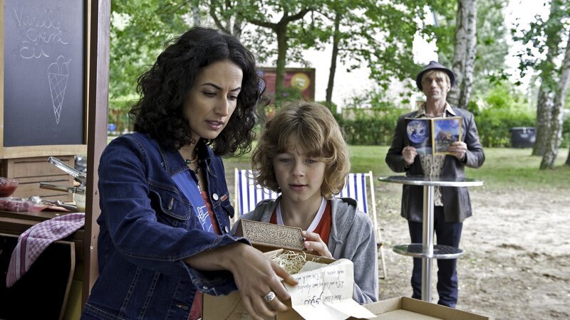 Yasemin (Sanam Afrashteh) hat ein Päckchen mit einer geheimnisvollen Botschaft bekommen. Nicht nur Max (Max Boekhoff) interessiert sich dafür, sondern auch der undurchsichtige Hasso Hotzrogger (André M. Hennicke). – Bild: ZDF und Antje Dittmann