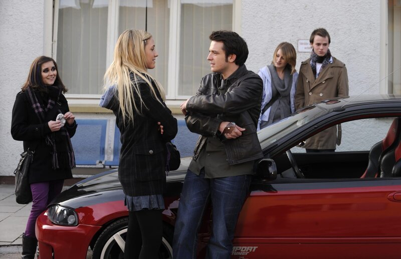 Miri ist begeisert von Floris Auto und möchte gleich eine Probefahrt machen. Von links: Nina Kreutzer (Andrea Schmitt), Miri (Alena Gerber) und Florian Brunner (Tommy Schwimmer). – Bild: BR/​Marco Orlando Pichler