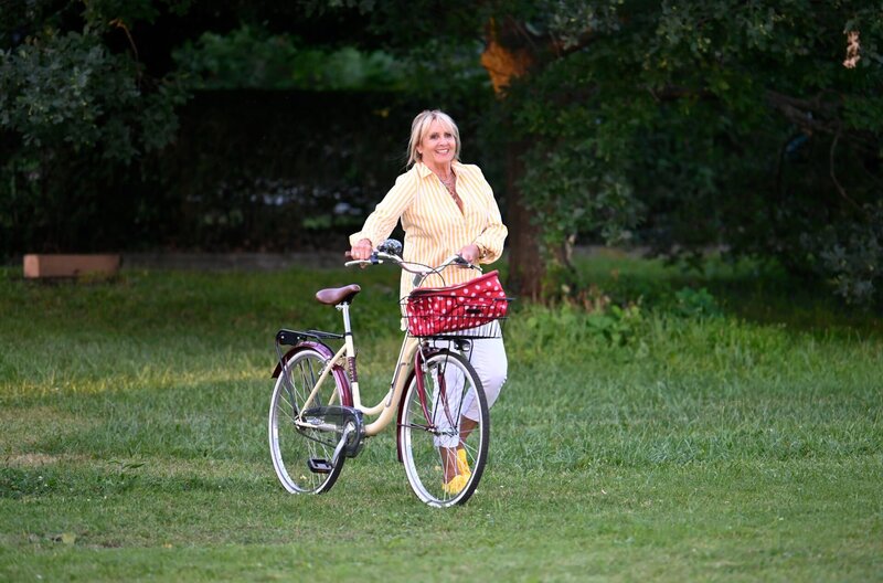 Mechthild Fehrenbach (Diana Körner) kommt mit dem Fahrrad und bringt Torte mit. – Bild: ARD/​Laurent Trümper