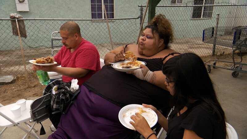 Lupe eating junk food in her wheelchair with her husband Gilbert. – Bild: Discovery Communications