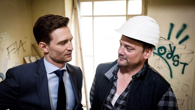 Maximilian Mertens (August Wittgenstein, l.) entdeckt den Riss in der Hauswand und trifft auf den Bauleiter Müller (Christian Beermann). – Bild: TVNOW /​ Christoph Assmann