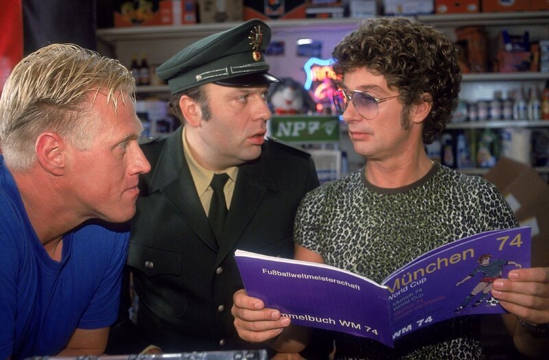 Ehrfürchtig schauen sich (v.li.) Harry (Norbert Heisterkamp) und Viktor (Waldemar Kobus) Atzes (Atze Schröder) Sammelalbum der Nationalelf von 1974 an. Doch dann stutzen sie – das Bild von Bernd Hölzenbein fehlt! – Bild: RTLup