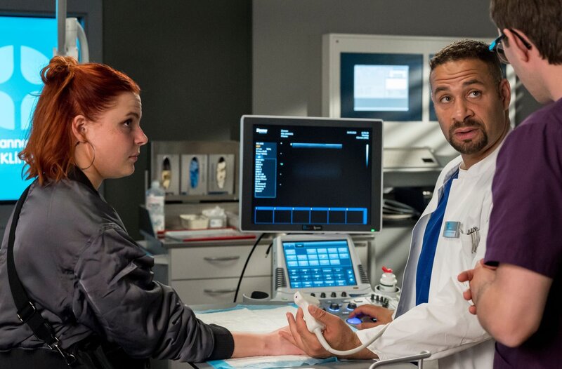 Der PJler Oliver Probst (Arne Kertész, r.) soll bei Dr. Matteo Moreau (Mike Adler, 2.v.r.) mitlaufen. Als die junge Gamerin Trixie Meyr (Carlotta Truman, l.) mit einem verletzten „Daddeldaumen“ ins Klinikum kommt, ist er Feuer und Flamme. Denn Olli ist ein großer Fan der schlagfertigen jungen Frau mit bunten Haaren. – Bild: ARD/​Jens-Ulrich Koch