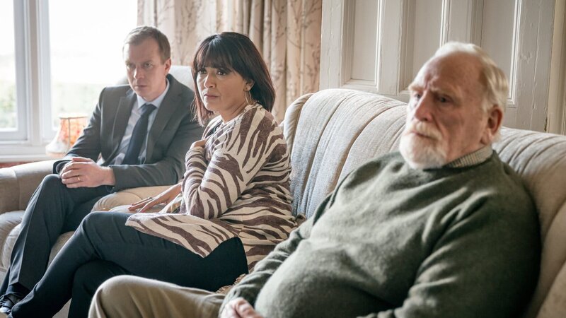 Mark Bradwell (Steven Robertson, l.) und Stella Bradwell (Sunetra Sarker, M.) möchten unbedingt wissen, ob der Todesfall des Kommissars mit dem Mord ihres Schwagers zusammenhängt. Bill Bradwell (James Cosmo, r.) zeigt dagegen mehr Verständnis gegenüber Lisa Armstrong. – Bild: ZDFneo