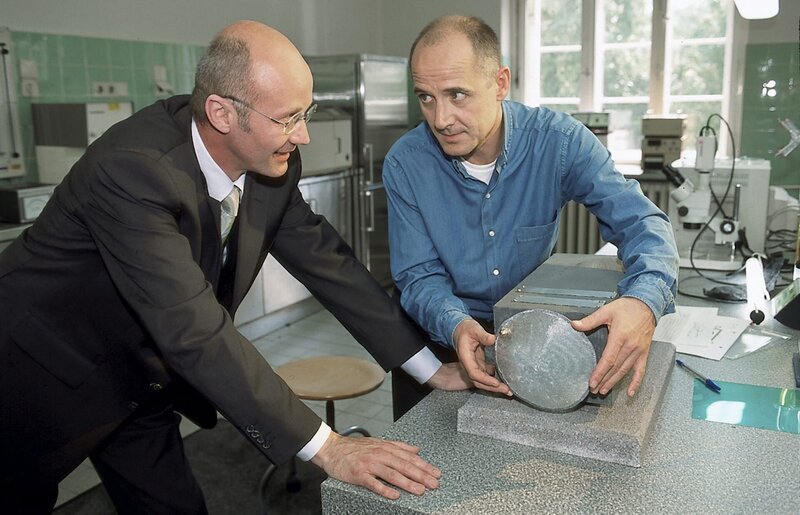 Gemeinsam bewundern Dr. Rainer Gottschalk (Chrisoph Wackernagel, l.) und Dr. Robert Kolmaar (Ulrich Mühe, r.) die Neutronenkanone von Ron Fugmann. – Bild: ZDF und Katrin Knoke