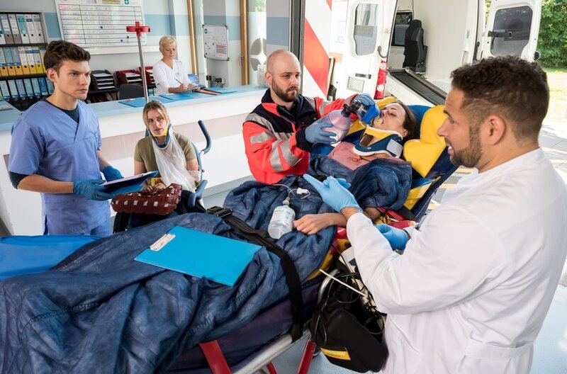 Heidi Kluttig (Merle Collet, 2.v.l.) bangt um das Leben ihrer Freundin Lena Schötz (2.v.r. mit Kompase). Dr. Matteo Moreau (Mike Adler, r.) und Florian Osterwald (Lion Wasczyk, l.) vermuten eine schwere Hirnverletztung bei der Patientin. – Bild: ARD/​Jens-Ulrich Koch