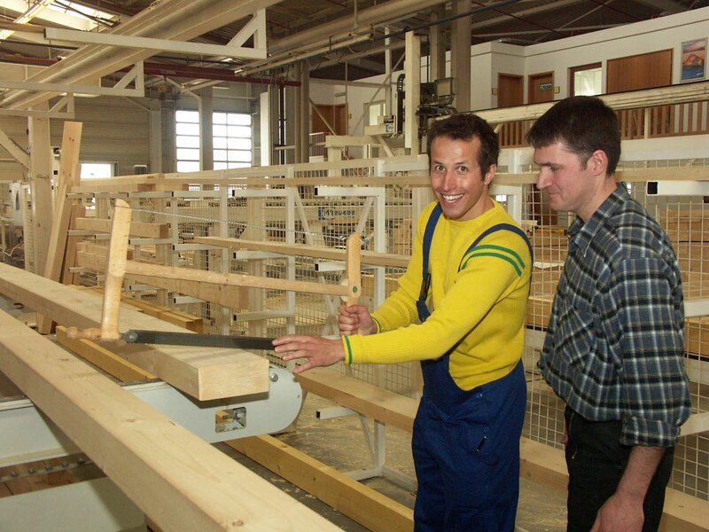Ein Zimmermann erklärt Willi Weitzel seine Arbeit. Hier entstehen Holzbalken für die Wände eines Fertighauses. – Bild: BR/​megaherz gmbh
