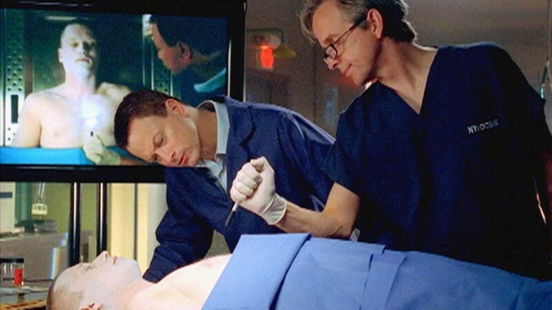 Dr. Hammerback (Robert Joy, r.) und Detective Taylor (Gary Sinise) untersuchen den Leichnam von Corporal Price (Darstellername unbekannt). – Bild: MG RTL D / CBS Dr. Hammerback (Robert Joy, r.) und Detective Taylor (Gary Sinise) untersuchen den Leichnam von Corporal Price (Darstellername unbekannt). – Bild: MG RTL D / CBS