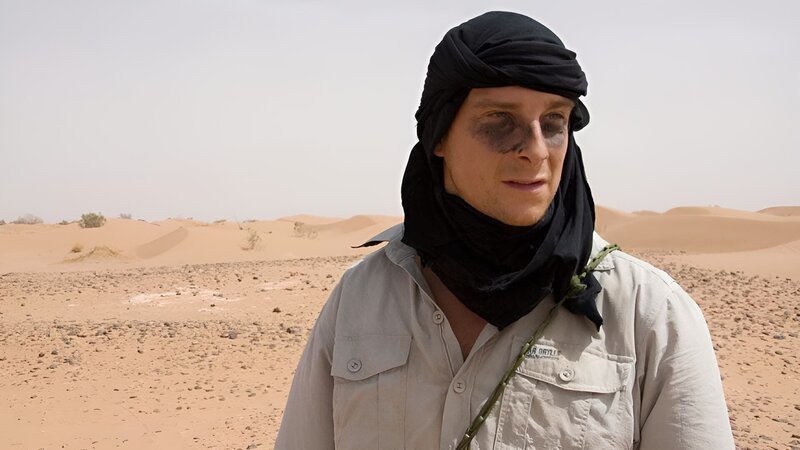 Host Bear Grylls on location in the Sahara desert with charcoal under his eyes to reduce the glare. – Bild: DCI