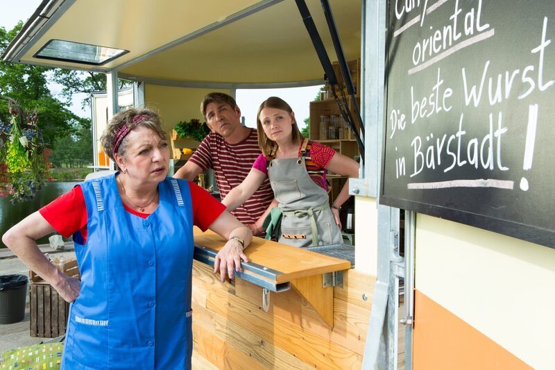 Konkurrentin und Wurstverkäuferin Hella Heistermeier (Manon Straché, l.) traut ihren Augen nicht: „Die beste Wurst von Bärstadt“? Sie allein verkauft die beste Wurst, nicht Fritz (Guido Hammesfahr, M.) und Charlie (Géraldine Raths, r.). – Bild: ZDF und Zia Ziarno