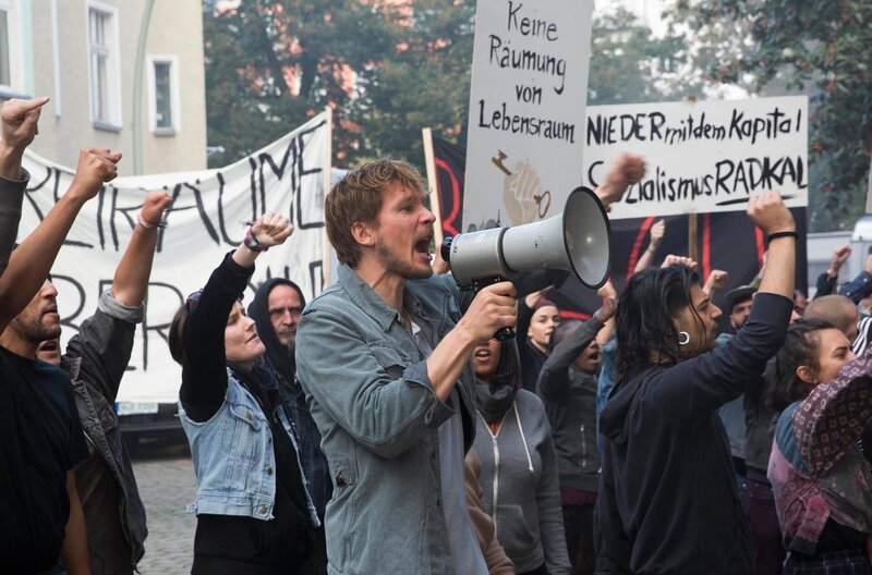 „Nieder mit dem Kapital“: Alex (Jacob Matschenz) auf einer Demo – Bild: ARD Degeto/​Studiocanal GmbH/​Frédéric Batier