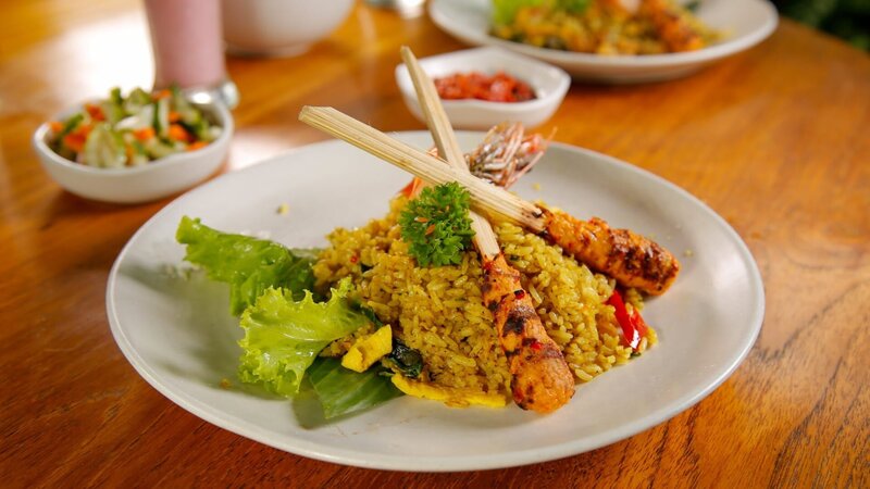 Nasi Goreng nach balinesischer Art ist gebratener Reis, der mit einer Vielzahl balinesischer Gewürze zubereitet und mit Hühnchen-Sate und Garnelen belegt wird – hier im Restaurant „Pulau Kelapa“ serviert. – Bild: ORF/​Warner/​The Travel Channel