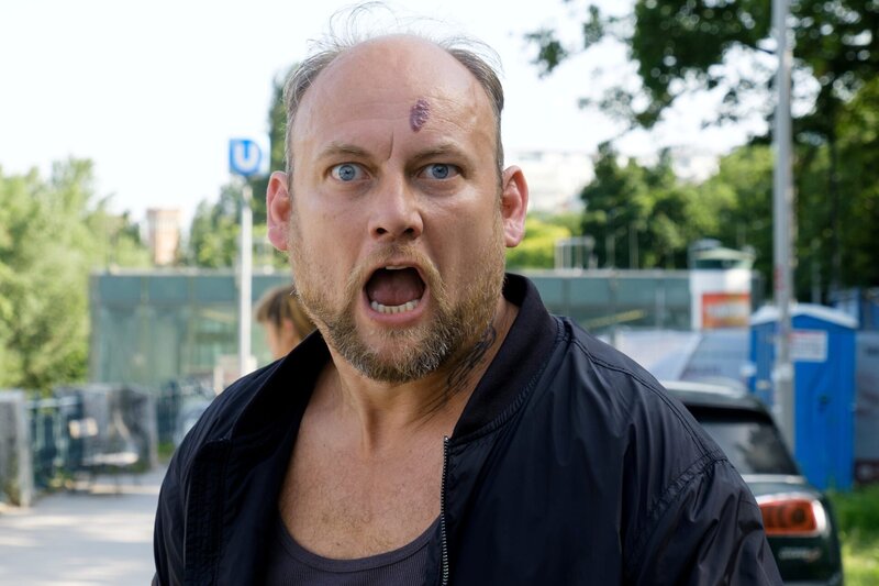 Penny befragt Louis über seine Beziehung zu Willi. (v.l.n.r.: Gruppeninspektorin Penny Lanz (Lilian Klebow), Louis Kubicka (Sebastian Waitzer), im Hintergrund: Komparsen). „SOKO Wien – Graues Leben“: Louis wird befragt. Fotograf: Petro Domenigg – Bild: Satel Film GmbH /​ ZDF und ORF