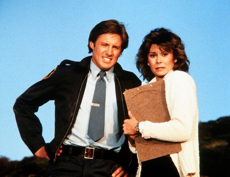 Lee (Bruce Boxleitner, l.) und Amanda (Kate Jackson) sehen zu, wie Lees geliebter Porsche in Flammen aufgeht. – Bild: CBS Television