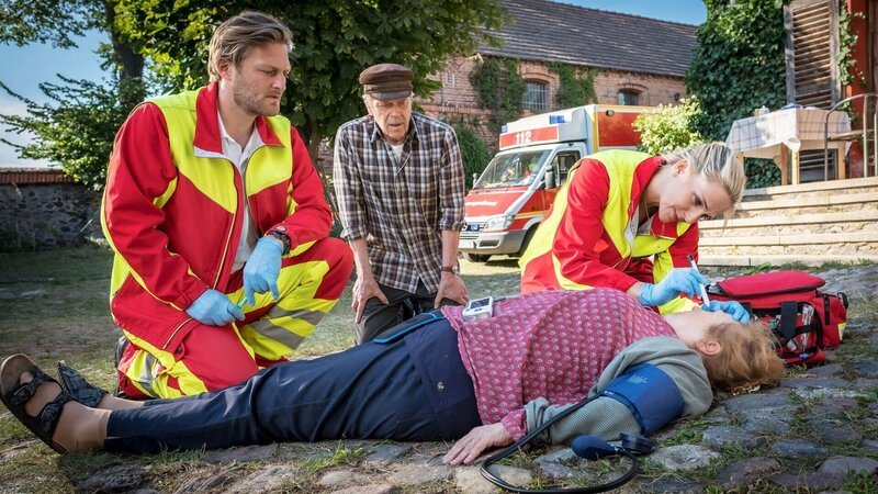 Nora Kaminski (Tanja Wedhorn) und Lars Hinrichs (Bo Hansen, li.) retten die Notfallpatientin Hilde Fischer (Franziska Troegner, liegend). Ihr dementer Ehemann Bodo (Jürgen Heinrich, hinten) schaut hilflos zu. – Bild: SRF/​ARD Degeto/​Boris Laewen