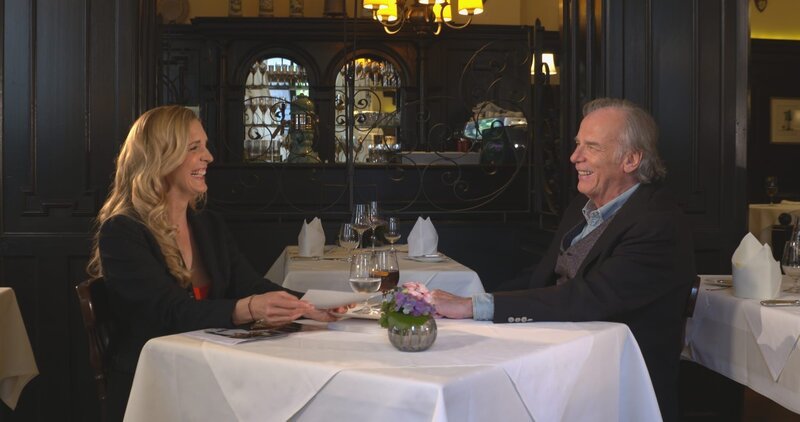 Wolfgang Fierek im Gespräch mit Moderatorin Caro Matzko. Er spielte in „Monaco Franze“ den Tierpark-Toni. – Bild: Thomas Schwendemann /​ BR, Zenofilm /​ BR/​Zenofilm/​Thomas Schwendemann