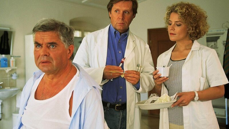 Modevertreter Bernd Sticker (Klaus Dahlen, l.) kommt wegen seines Übergewichts in Stefans (Sigmar Solbach) Praxis. Sprechstundenhilfe Marie Luise (Christiane Brammer) assistiert bei der Untersuchung. – Bild: MG RTL D /​ Elke Werner