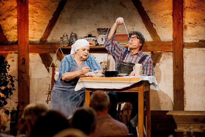 Aus der Flädlessuppe von Lena (Hillu Stoll) fischt Mattheis (Franz Auber) alte Putzlumpen heraus. – Bild: SWR/​Ronny Zimmermann