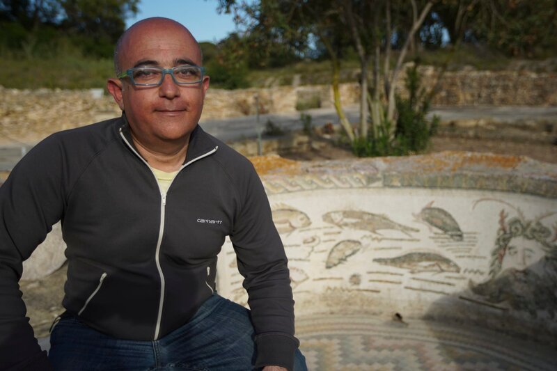Dr. Mounir Fantar next to a sea themed mosaic in the garden of the House of Nymphs – Bild: Blink Films
