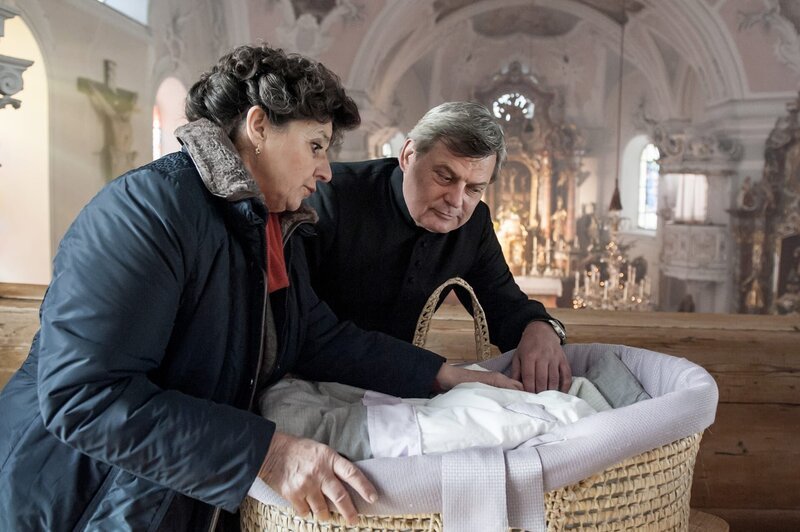 Lisbeth Gruber (Monika Baumgartner, l.) und der Pfarrer (Franz Weichenberger) entdecken nach der Chorprobe ein ausgesetztes Kind. – Bild: ZDF und Stefanie Leo