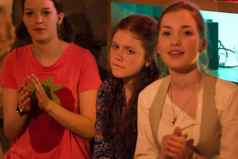 Hedda (Juliette Hartig, mitte) bekommt Lampenfieber als sie die Talente ihrer Mitschüler sieht. Weitere Zuschauer: Roxy (Helene Mardicke, li.) und Miriam (Jelena Herrmann, re.). – Bild: MDR/​Katharina Simmet