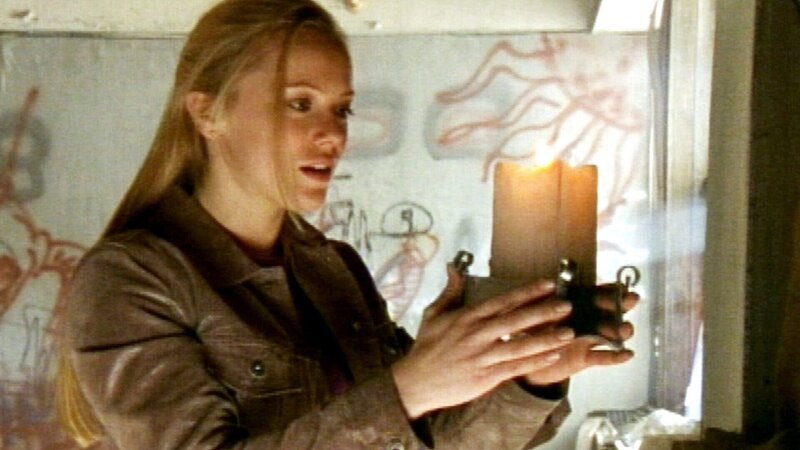 Beinahe hätte der Dieb Caitlin (Tanja Reichert) getötet, aber als plötzlich eine Wand zu brennen anfängt läßt er von seinem Opfer ab und verschwindet. Gleich darauf löschen sich die Flammen von selbst und Caitlin entdeckt die Kerze ihrer Mutter an der Wand … – Bild: RTLZWEI