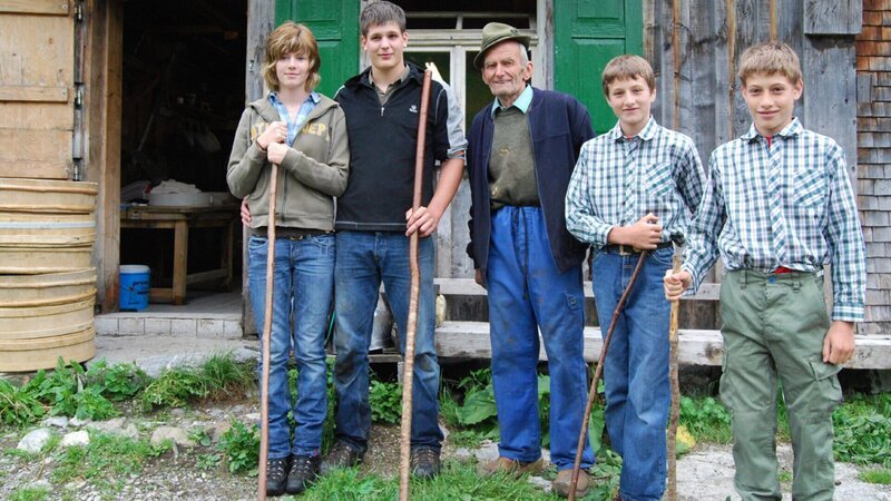 Der 85-jährige Bergbauer Anton Moosbrugger (M.) zeigt seinem Neffen Christoph (2. v. l.), dessen Freundin Katharina (l.) und den Enkeln Johannes (4. v. r. ) und Matthias welche Aufgaben sie auf der Hochalpe erwarten. – Bild: ZDF und Peter Klotz