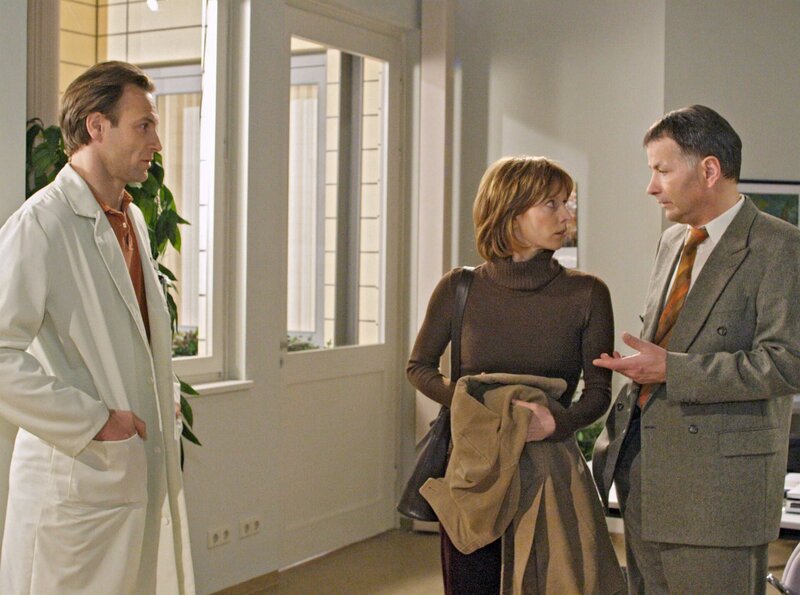 Susanne Frenzen (Anka Baier) ist fest überzeugt, dass Dr. Martin Stein (Bernhard Bettermann, li.) bei der Operation ihres Mannes vor einiger Zeit ein Kunstfehler passiert ist. Als sie ihm in der Sachsenklinik wiederbegegnet, bittet sie Dr. Roland Heilmann (Thomas Rühmann, re.) ihn von ihrem Mann fern zu halten. – Bild: MDR/​Krajewski