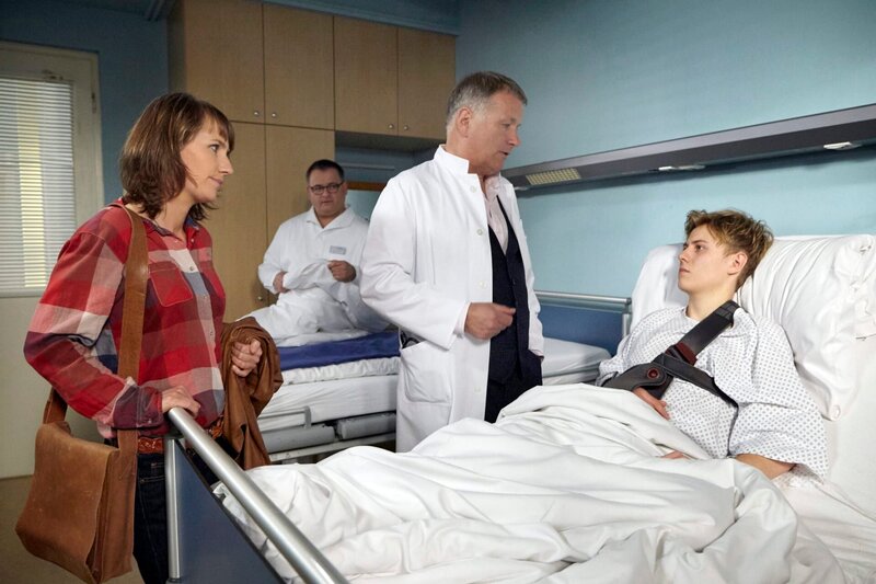 Hannes Cremer (Max Schimmelpfennig, rechts) wurde an der Schulter operiert und nun verordnet ihm Dr. Roland Heilmann (Thomas Rühmann, 2. von rechts) zwei Wochen Ruhe zur Wundheilung. Doch Hannes ist Umweltaktivist und eigentlich auf dem Weg in ein Camp. Er fragt seine Mutter Ines (Angela Meyer, links) herablassend, ob sie nun zufrieden sei. Er werde jedenfalls nicht in der Klinik bleiben, sondern zum Aktivistencamp fahren. Hans-Peter Brenner (Michael Trischan) hat keinerlei Verständnis für die radikale Art des Teenagers. – Bild: MDR/​Saxonia Media Filmproduktion/​Wernicke