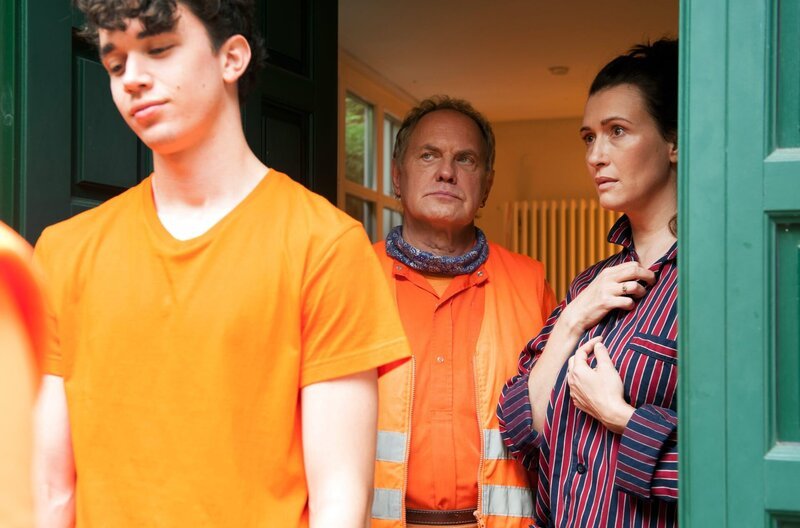 ARD Degeto DIE DREI VON DER MÜLLABFUHR – MISSION ZUKUNFT, am Freitag um 20:15 Uhr im ERSTEN. Kneifen gilt nicht: „Käpt’n“ Werner Träsch (Uwe Ochsenknecht) holt Dennis (Ben Litwinschuh, li.) höchstpersönlich bei seiner Mutter Franziska Kruse (Claudia Mehnert) zum Dienst ab. – Bild: ARD Degeto/​Britta Krehl